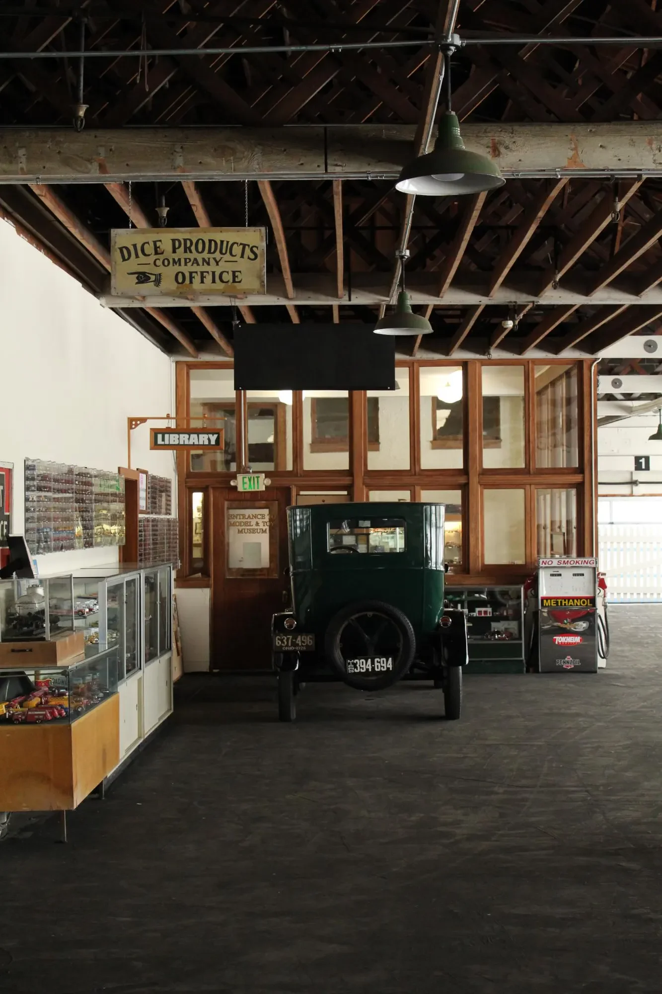 Vintage automobile displayed beside model-car cases and a gasoline pump inside a museum
