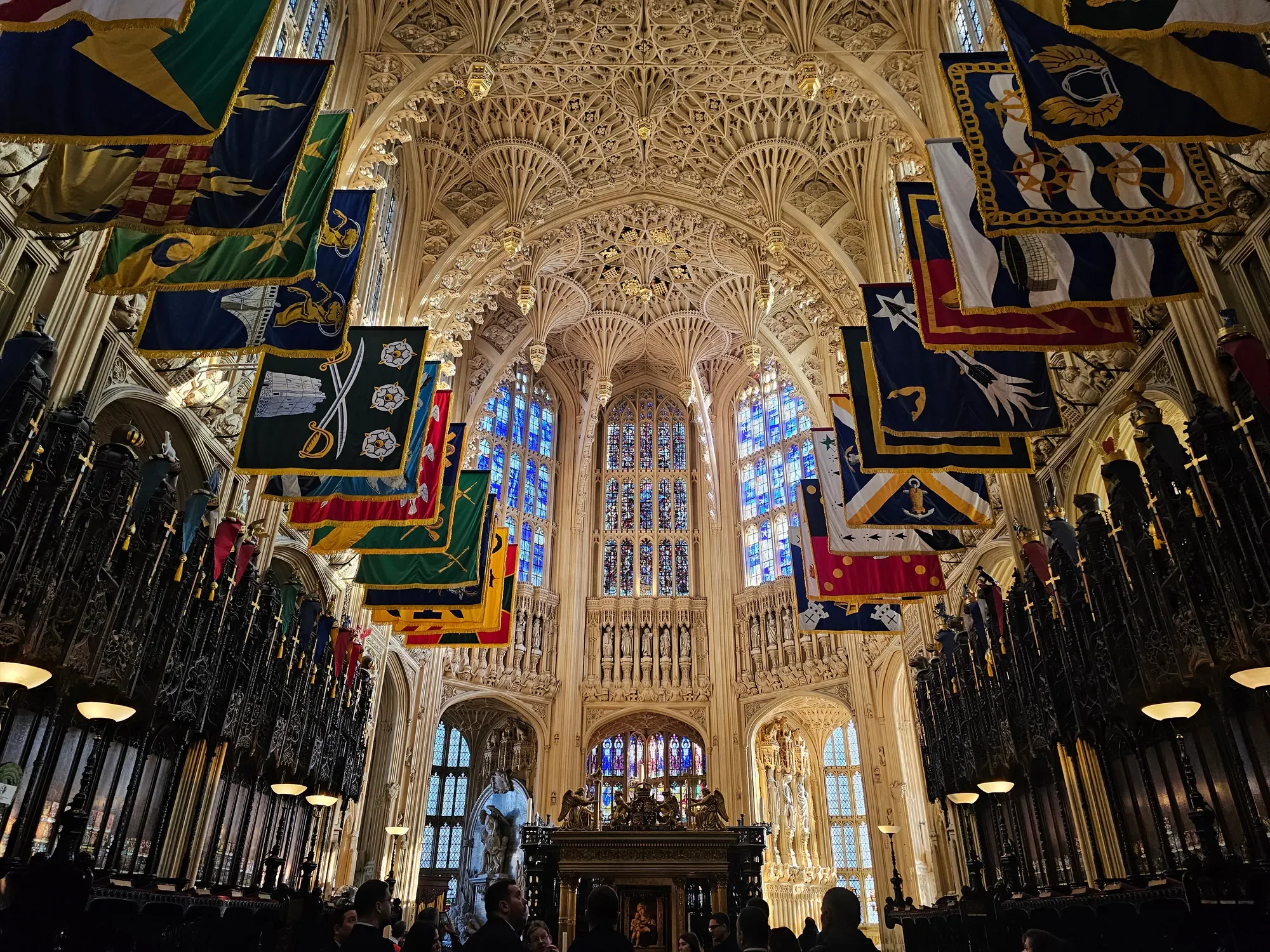 Ornate vaulted ceiling and ceremonial flags at Westminster Abbey